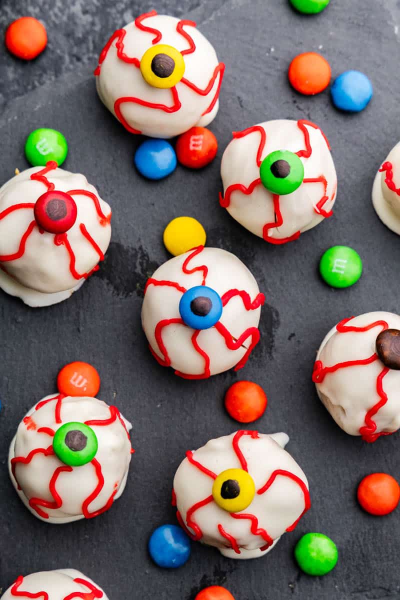 Overhead view of a few pumpkin truffle eyeballs with scattered mini M&M's.