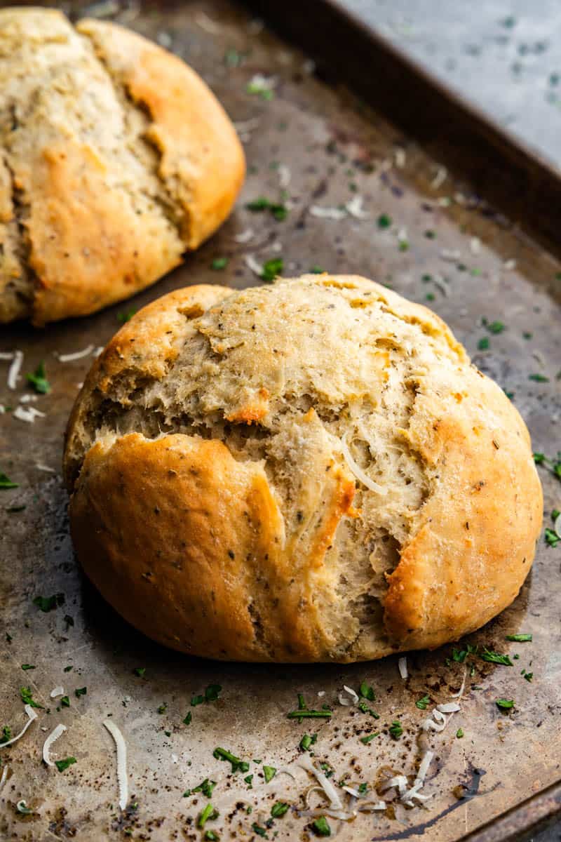 Two loaves of garlic and parmesan herb bread on a baking sheet.