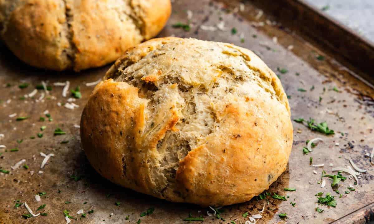 A loaf of garlic parmesan herb bread on a baking sheet.