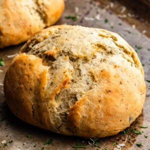 A loaf of garlic parmesan herb bread on a baking sheet.