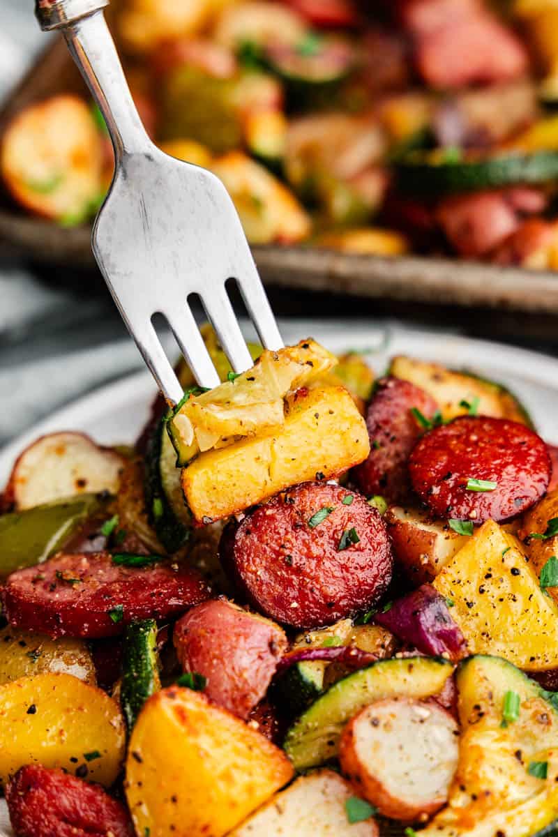 A close-up photo of vegetables and sausage spearing a fork off a plate.