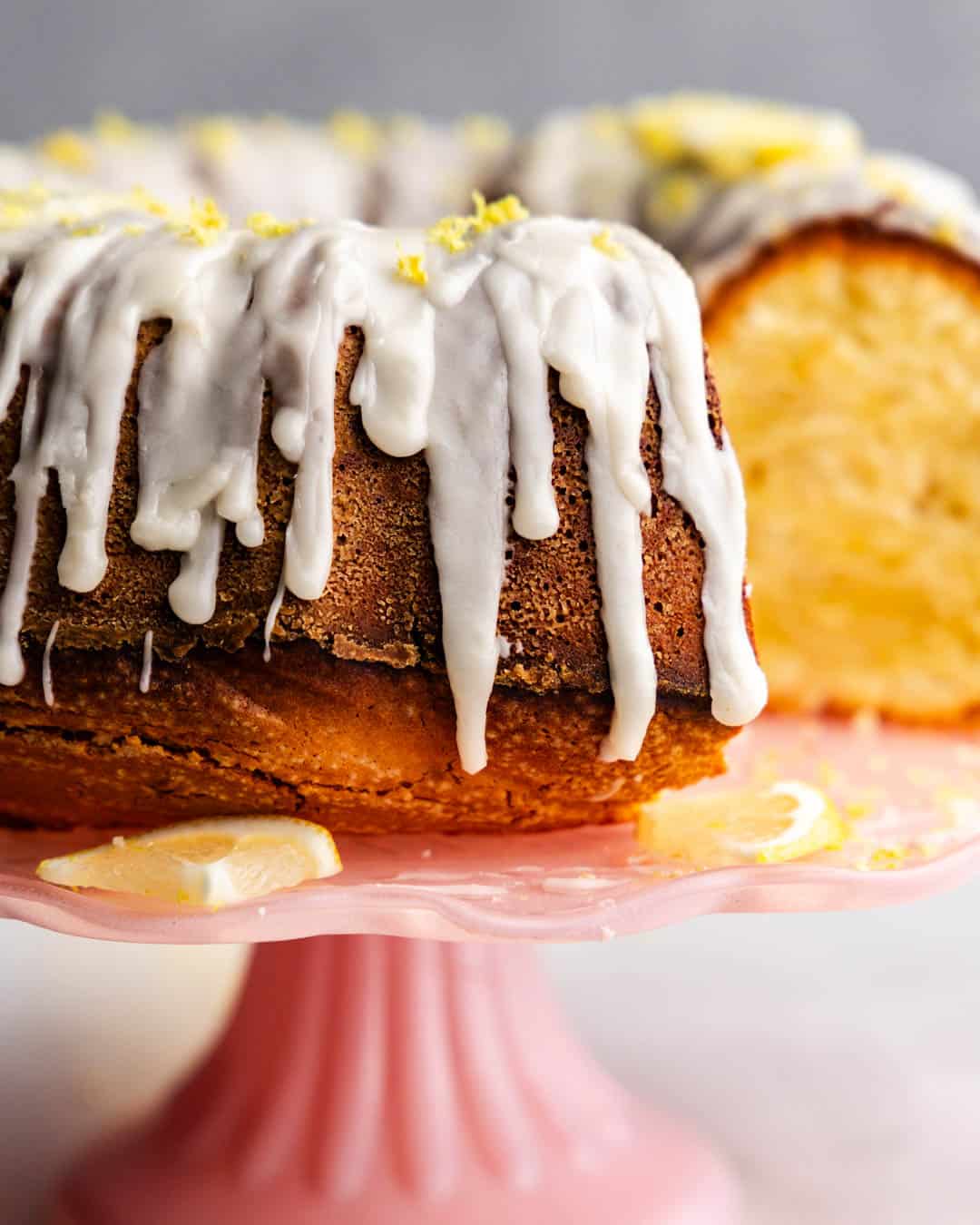 A lemon pound cake bundt cake on a pink cake pedestal.