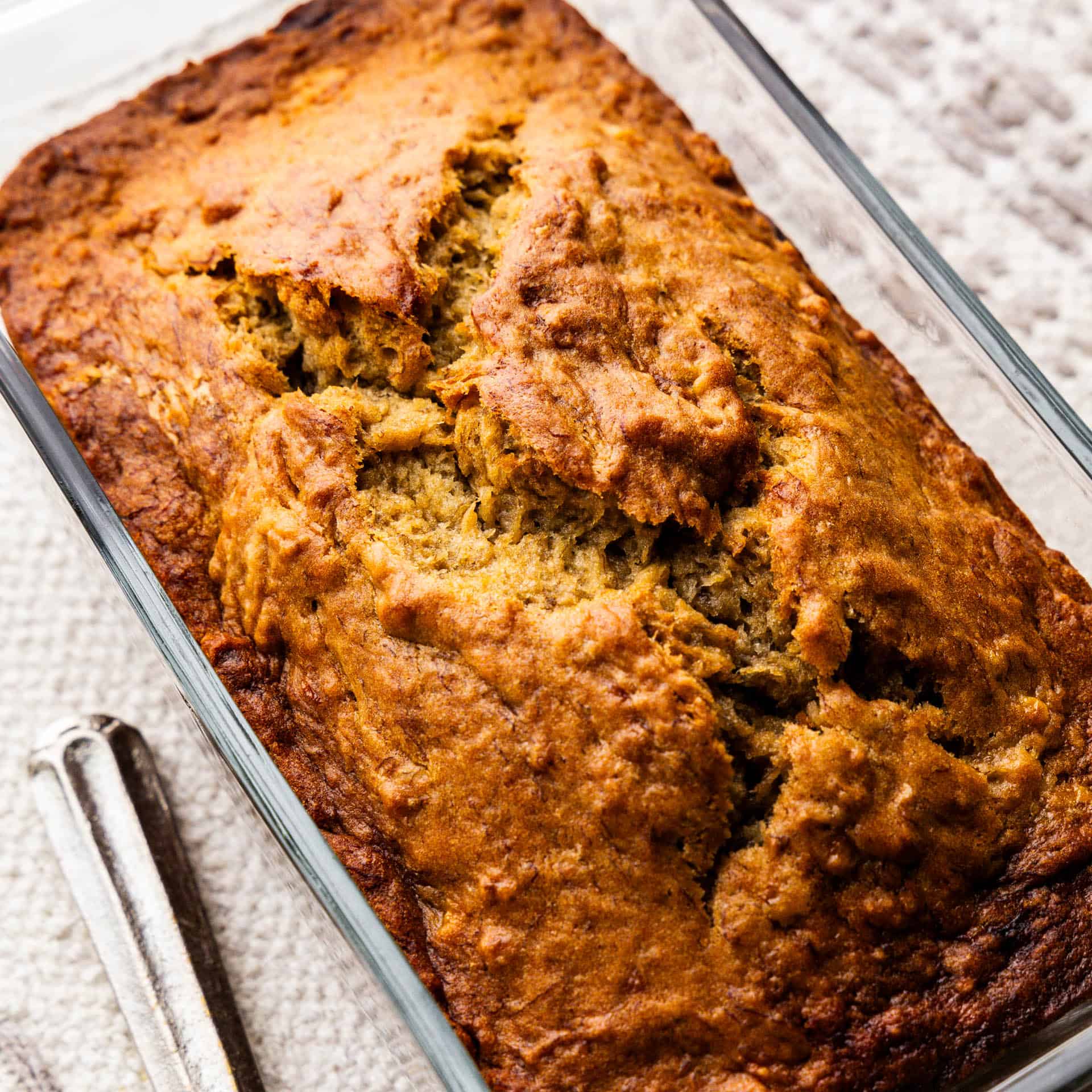 An angled overhead view of a loaf of banana bread still in the loaf pan.