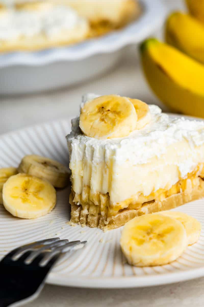 Slice of banana cream pie on white plate