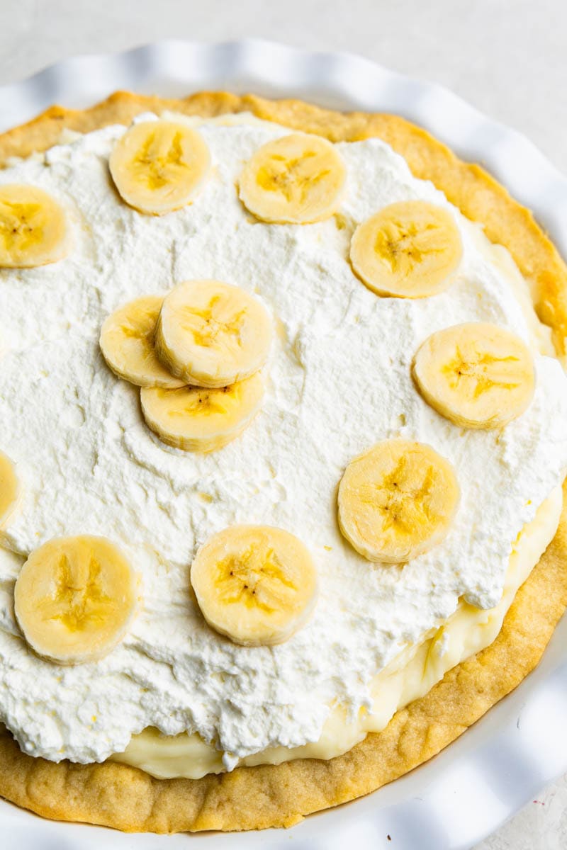 A whole banana cream pie on a white pie plate