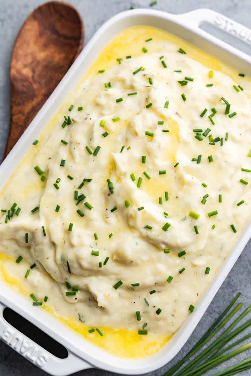 A close up overhead shot of a casserole dish filled with creamy herbed butter mashed potatoes.