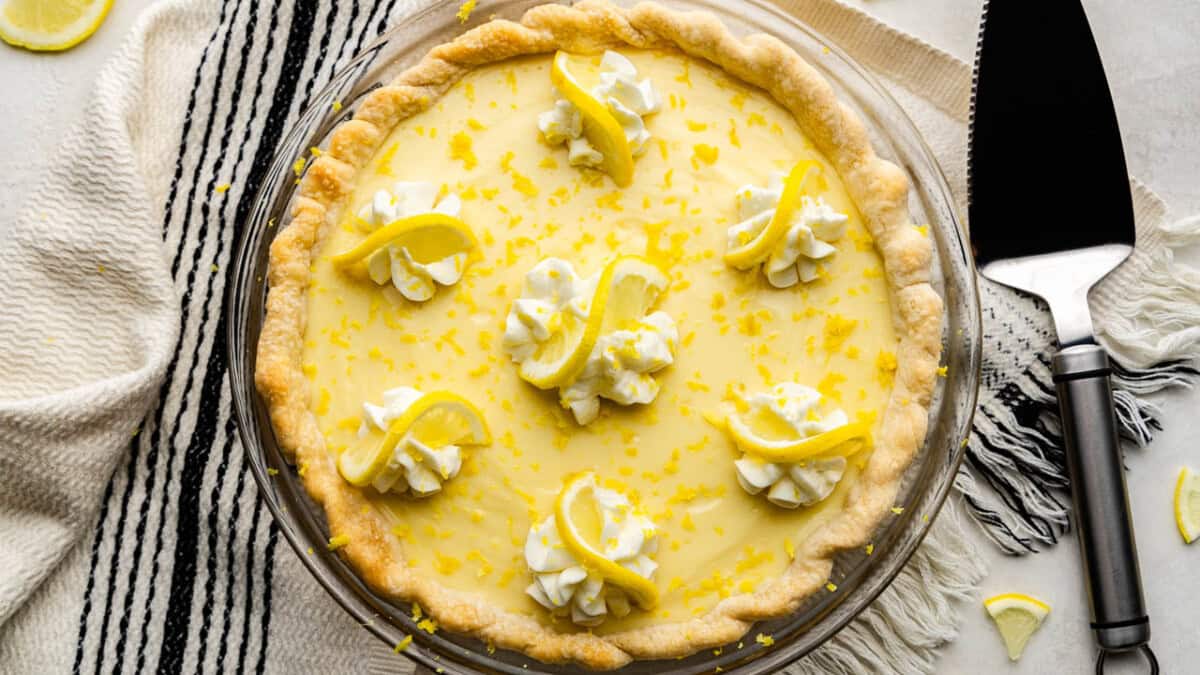 An overhead shot of a creamy lemon pie set next to a pie server spatula.