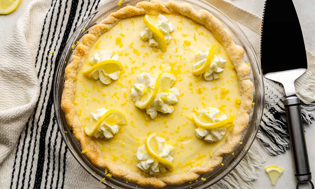 An overhead shot of a creamy lemon pie set next to a pie server spatula.