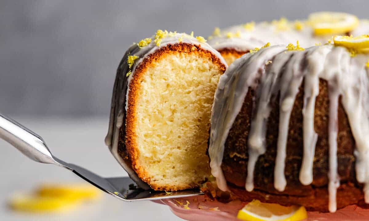 A slice of lemon poundcake being removed from the bundt cake loaf.