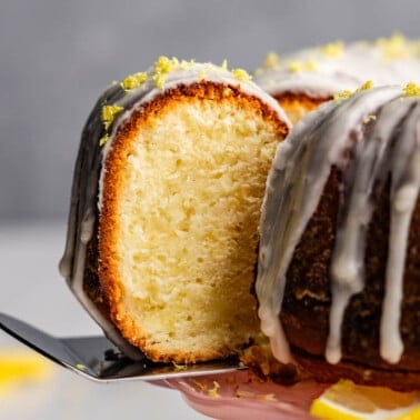 A slice of lemon poundcake being removed from the bundt cake loaf.