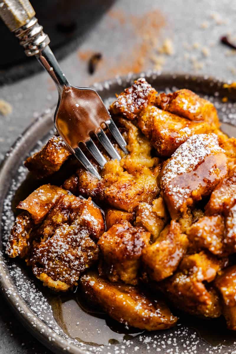 A gray plate of pumpkin french toast casserole with a fork sticking out ready to dish out a bite.