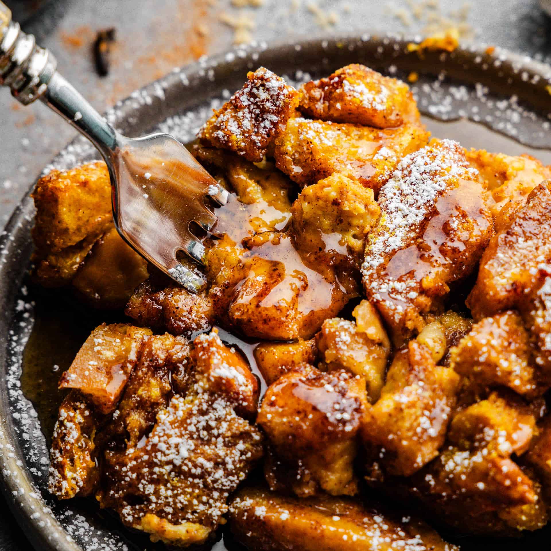 A close up view of a plate of pumpkin french toast casserole on a plate with a fork sticking out.