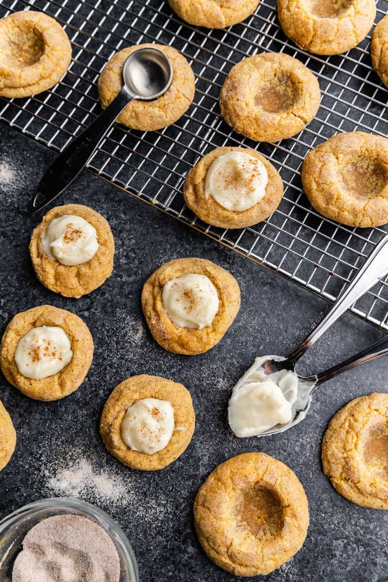 An overhead view of Pumpkin Cheesecake Thumbprint Cookies on a wire cooling rack.