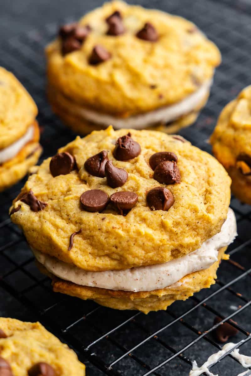 A close up of a pumpkin chocolate chip cookie sandwich with a cream filling