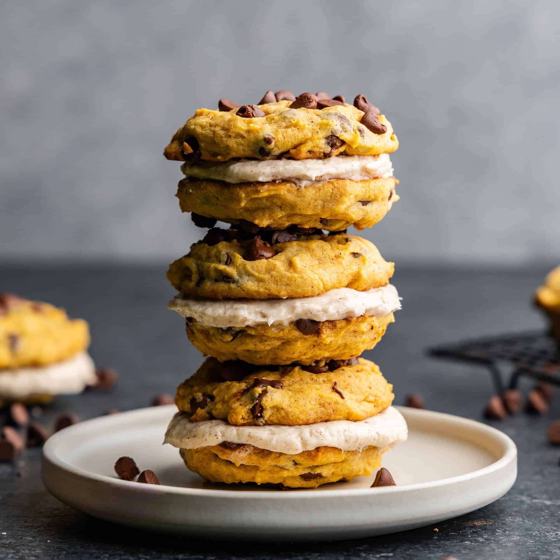 Three pumpkin sandwich cookies stacked on top of each other on a plate.