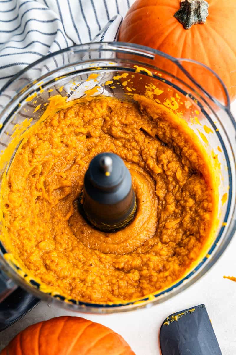 The bowl of a food processor filled with pumpkin puree.