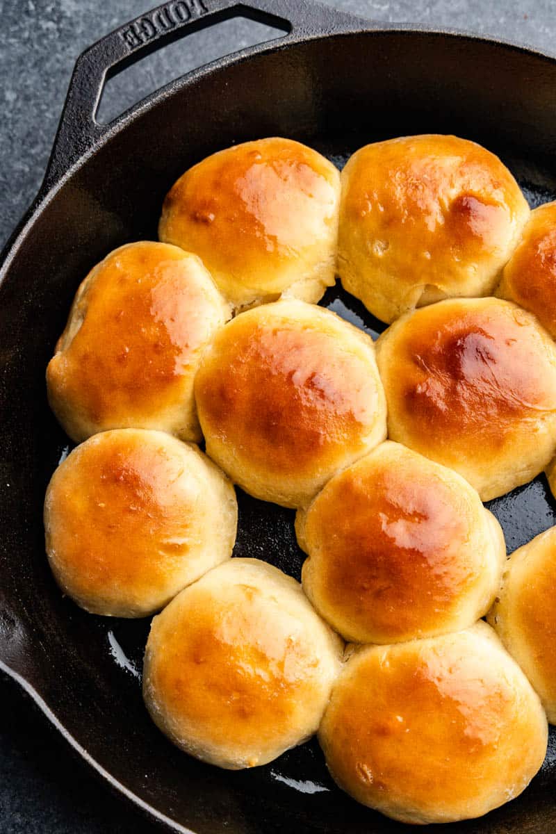 An overhead view into a cast iron filled with golden brown rolls.