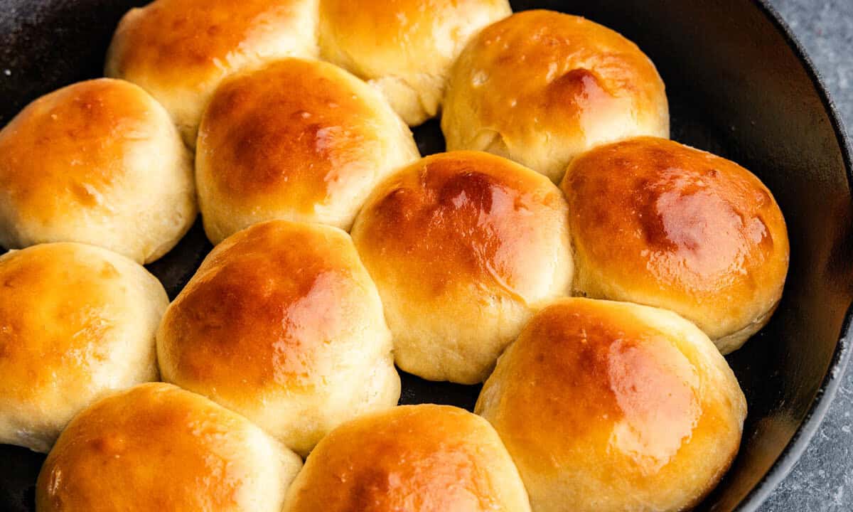 A cast iron skillet filled with golden brown rolls.