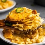 A scoop of jalapeno scalloped potatoes dishing a serving onto a plate.