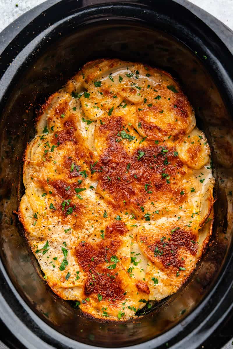 Overhead view of a slow cooker crock full of scalloped potatoes.