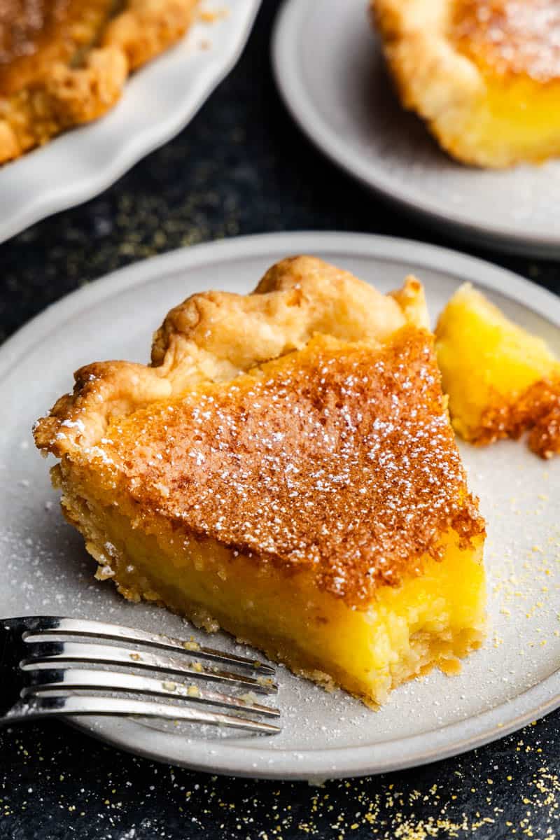 Pieces of chess pie on a plate. A fork is resting on the plate as the first bite is taken.