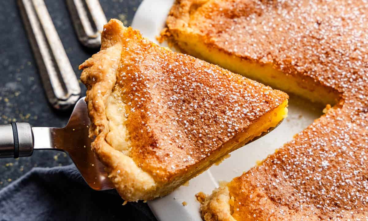 A slice of chess pie being lifted out of the pan by a pie server.