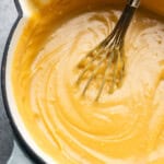 An overhead look into a pan of warm homemade butterscotch pudding with a whisk sticking out.
