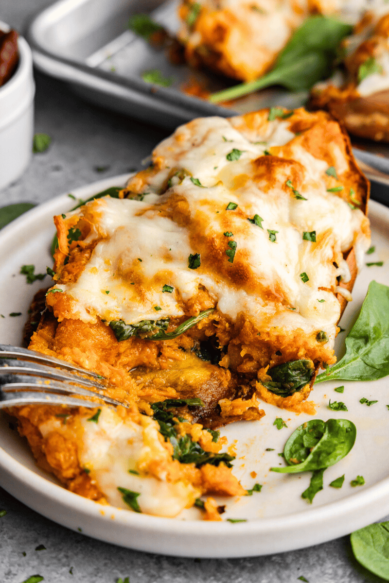 A close up view of a chipotle twice baked sweet potato on a plate. It's been cut into and a few bites taken out.