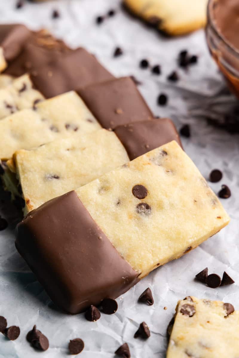 chocolate chip shortbread cookies dipped in chocolate arranged on parchment paper