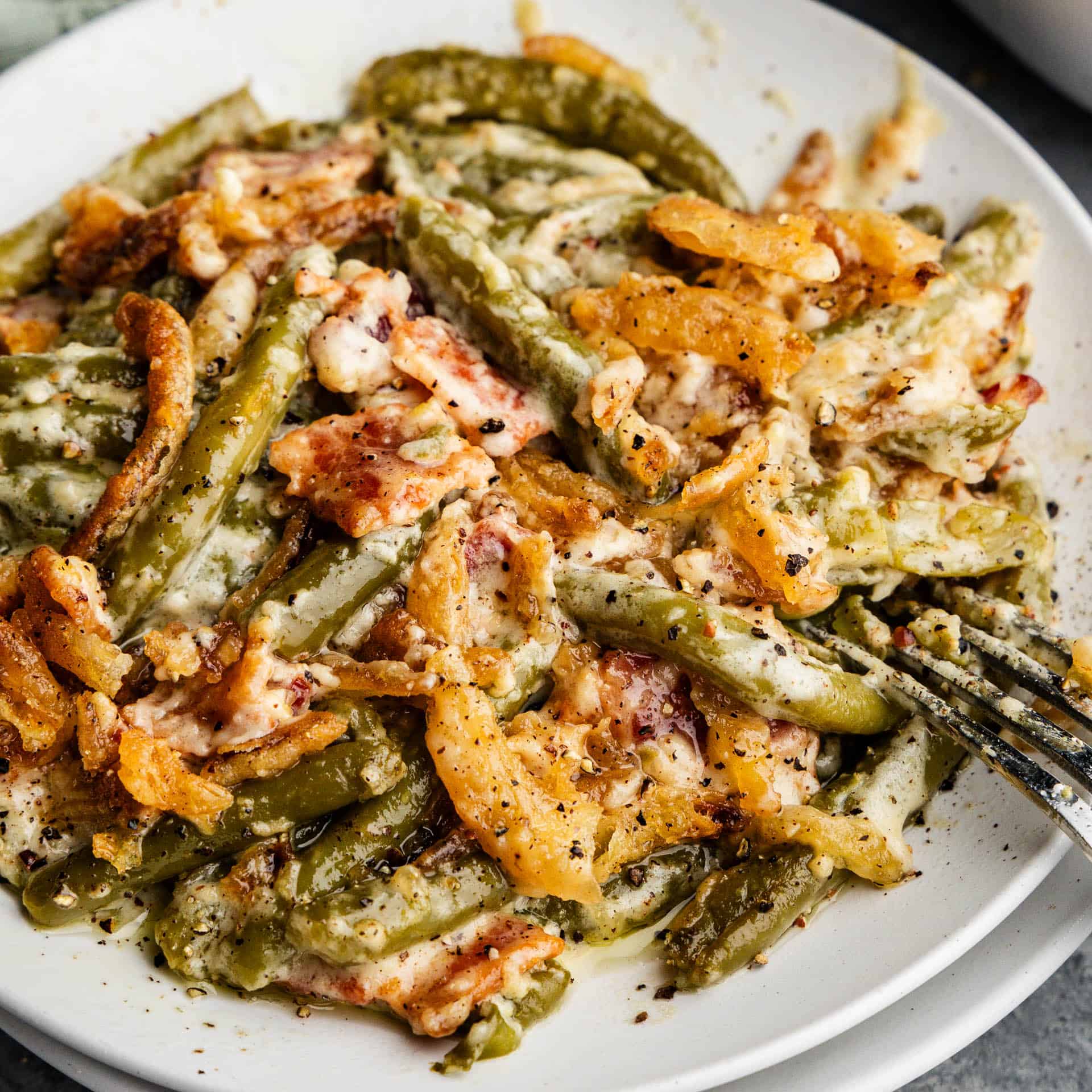 A close up view of a plate of green bean casserole with crispy onions on top.