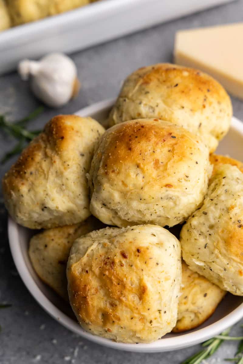 freshly baked garlic parmesan herb dinner rolls in white bowl