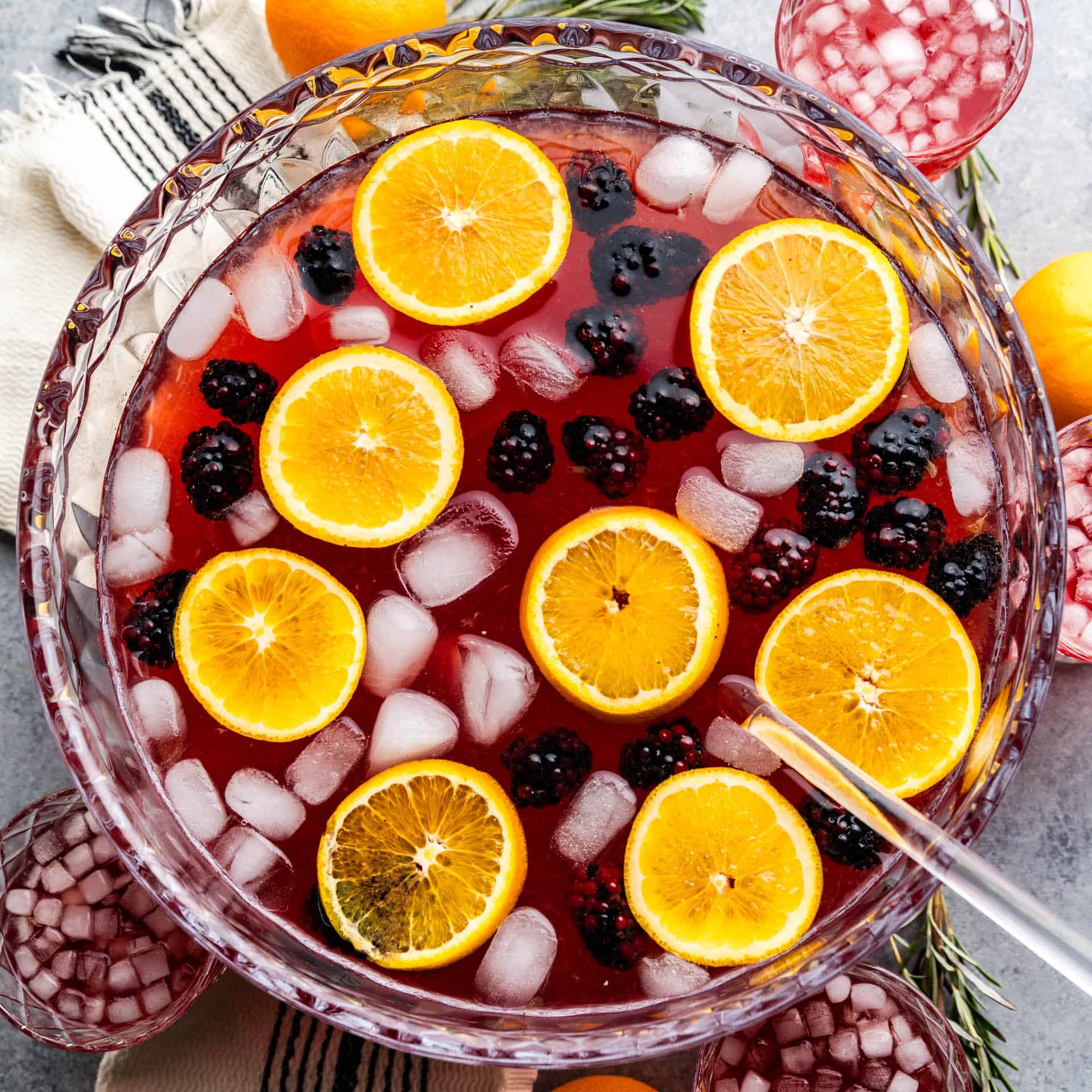 An overhead view into a punch bowl filled with holiday punch, orange slices and fresh blackberries.