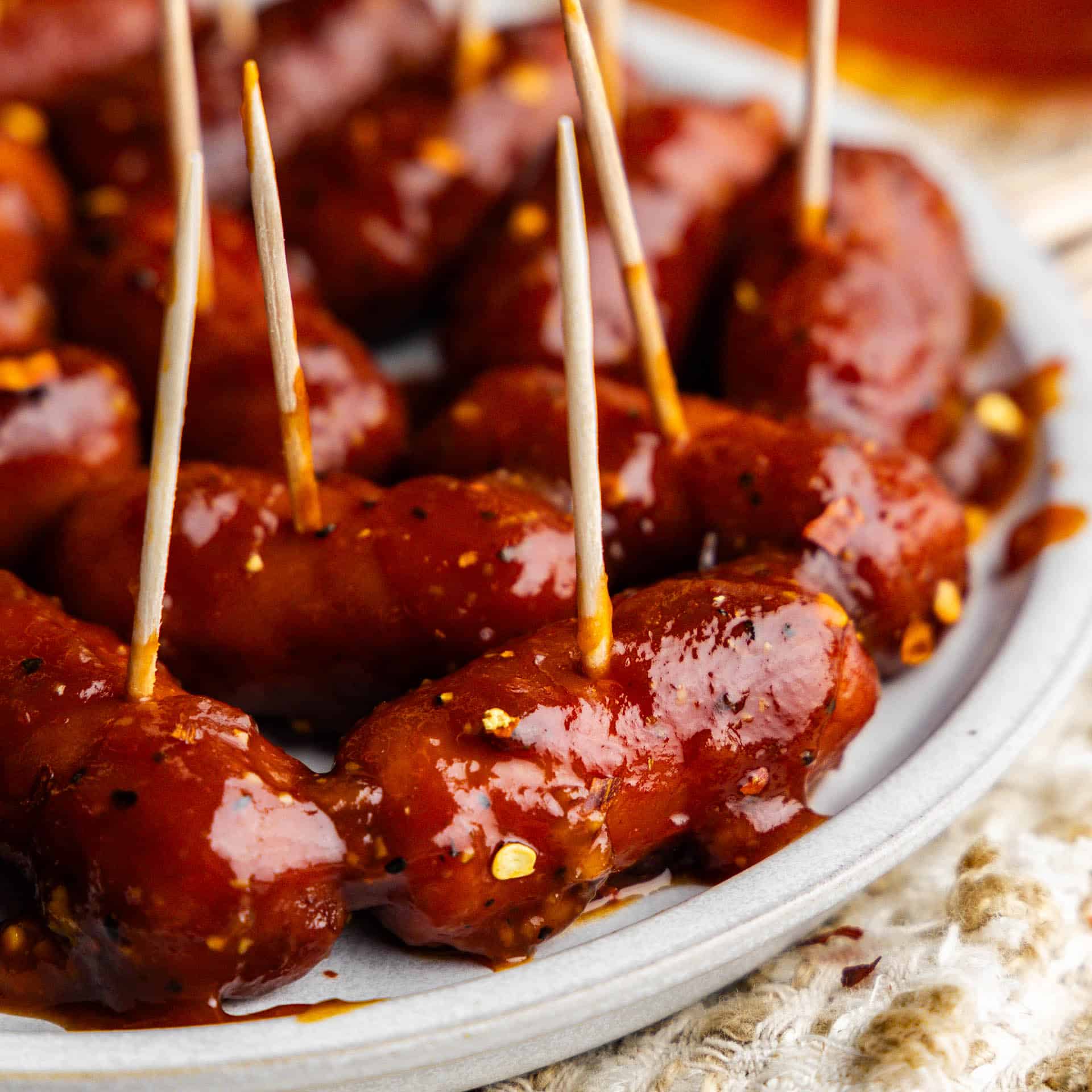 A plate of hot honey garlic lil smokies with toothpicks sticking out.