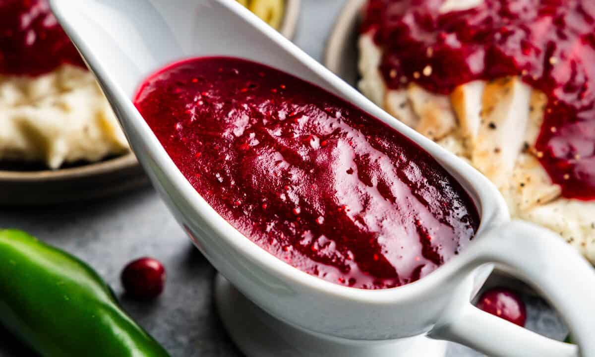 An overhead close up view into a white gravy boat filled with jalapeno cranberry sauce.