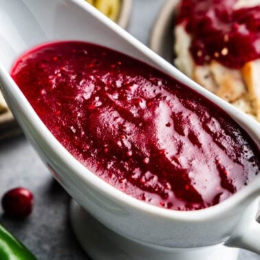 An overhead close up view into a white gravy boat filled with jalapeno cranberry sauce.