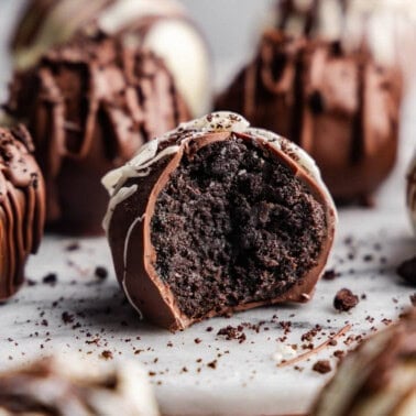 A close-up of Oreo truffles arranged on a table, with one in the front with a bite taken out