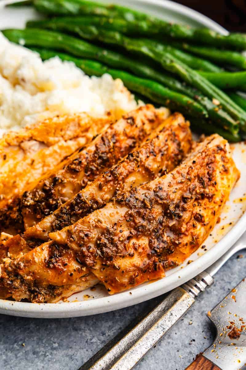 sliced turkey breast on plate with mashed potatoes and green beans