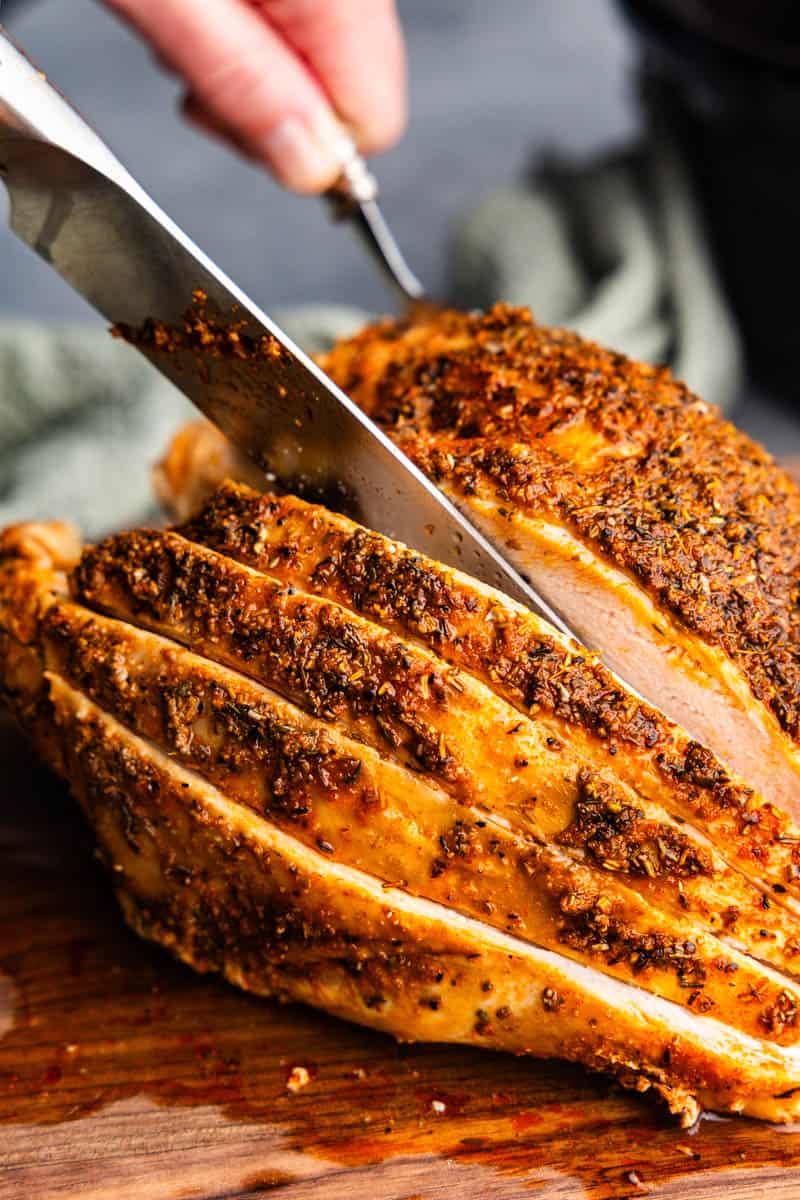 hand carving turkey breast on platter