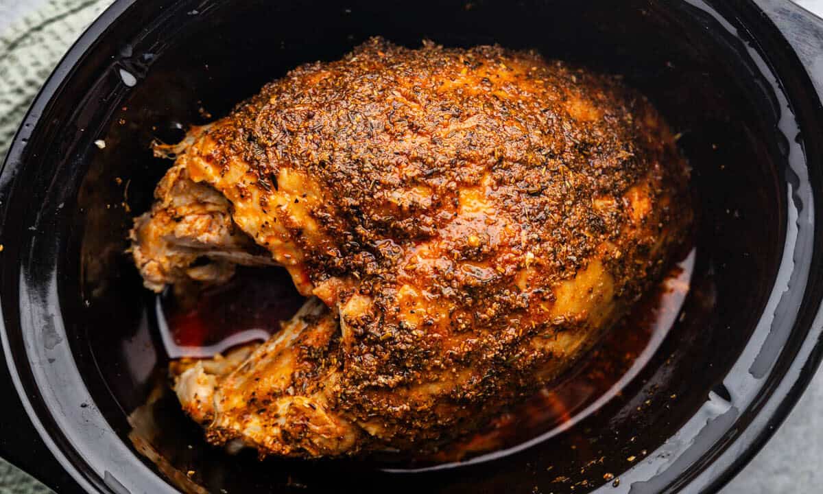 An overhead view of a turkey breast in the crock of a slow cooker.