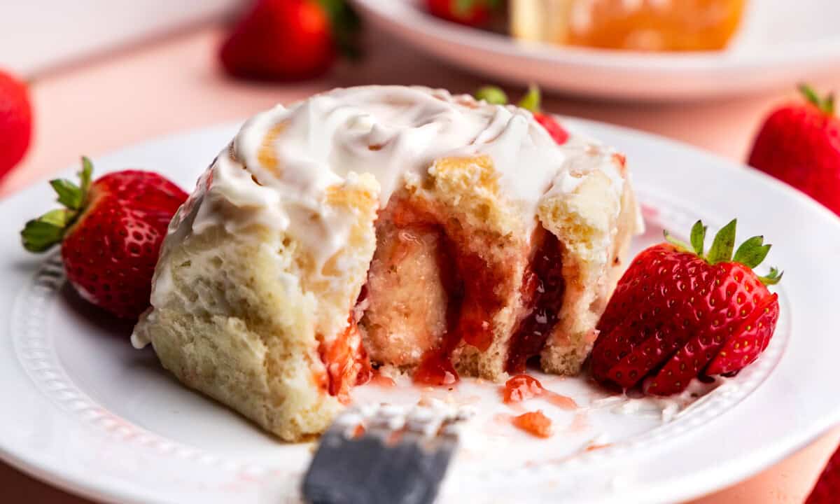 side view of strawberry roll on plate with bite taken out of it