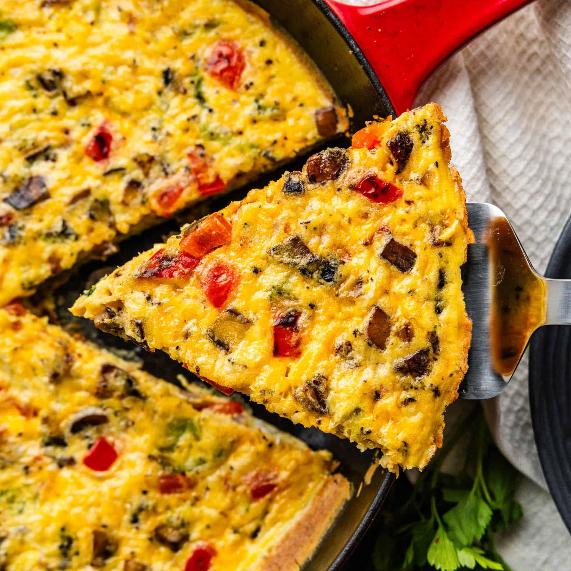 A slice of frittata being pulled from a cast iron skillet.