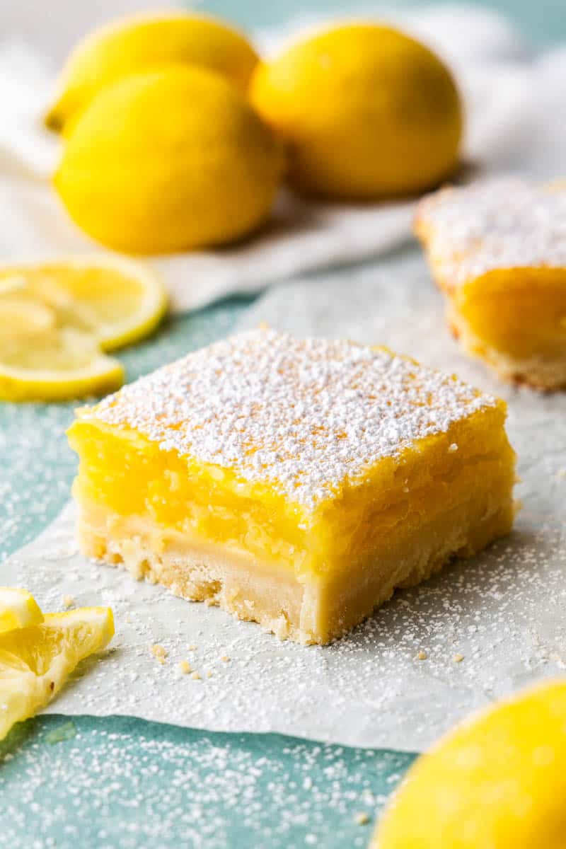 A close up view of a lemon bar on parchment paper.