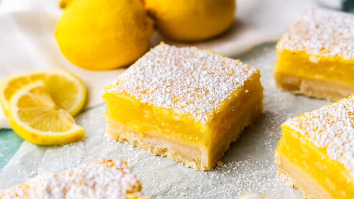 A close up view of a lemon bar on parchment paper.