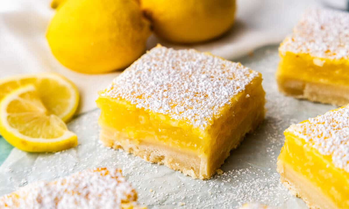 A close up view of a lemon bar on parchment paper.