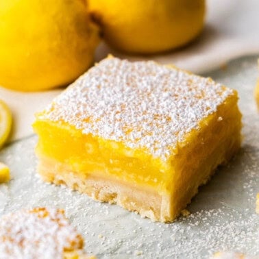 A close up view of a lemon bar on parchment paper.