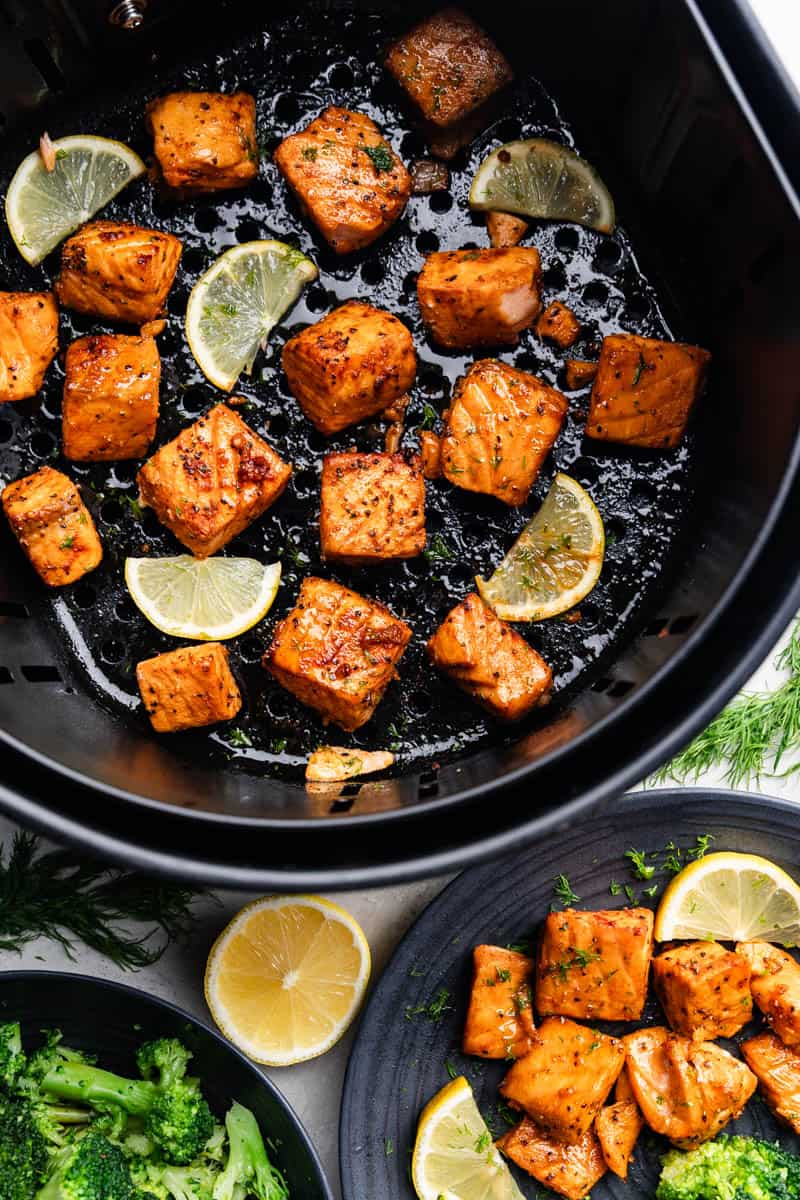 An overhead view of salmon bites in the basket of an air fryer.