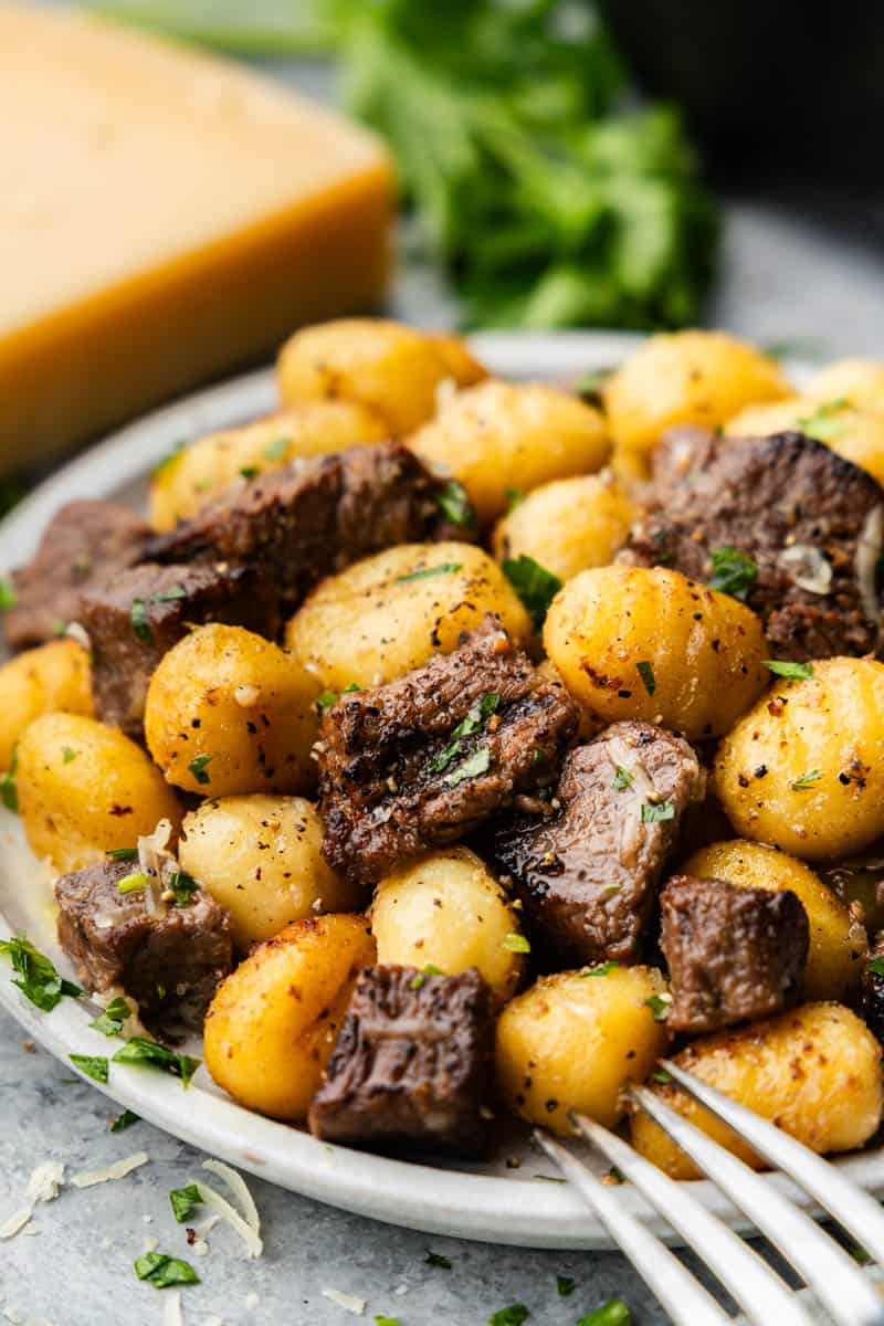 A close up view of a plate of steak bites and gnocchi.