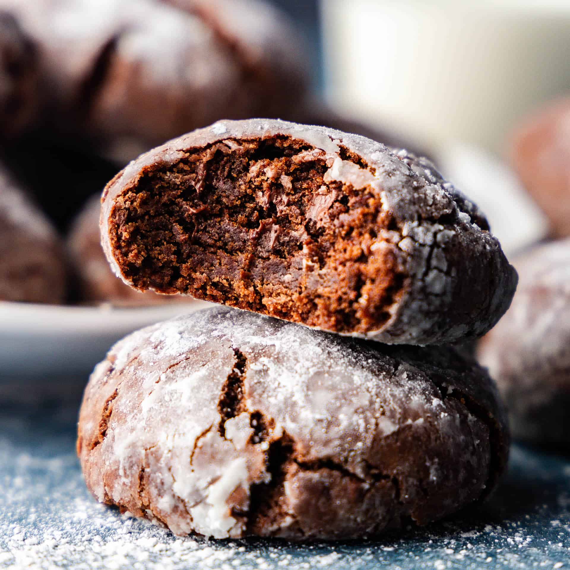 A close up view stack of two chocolate crinkle cookies with the top one having a bite taken out.