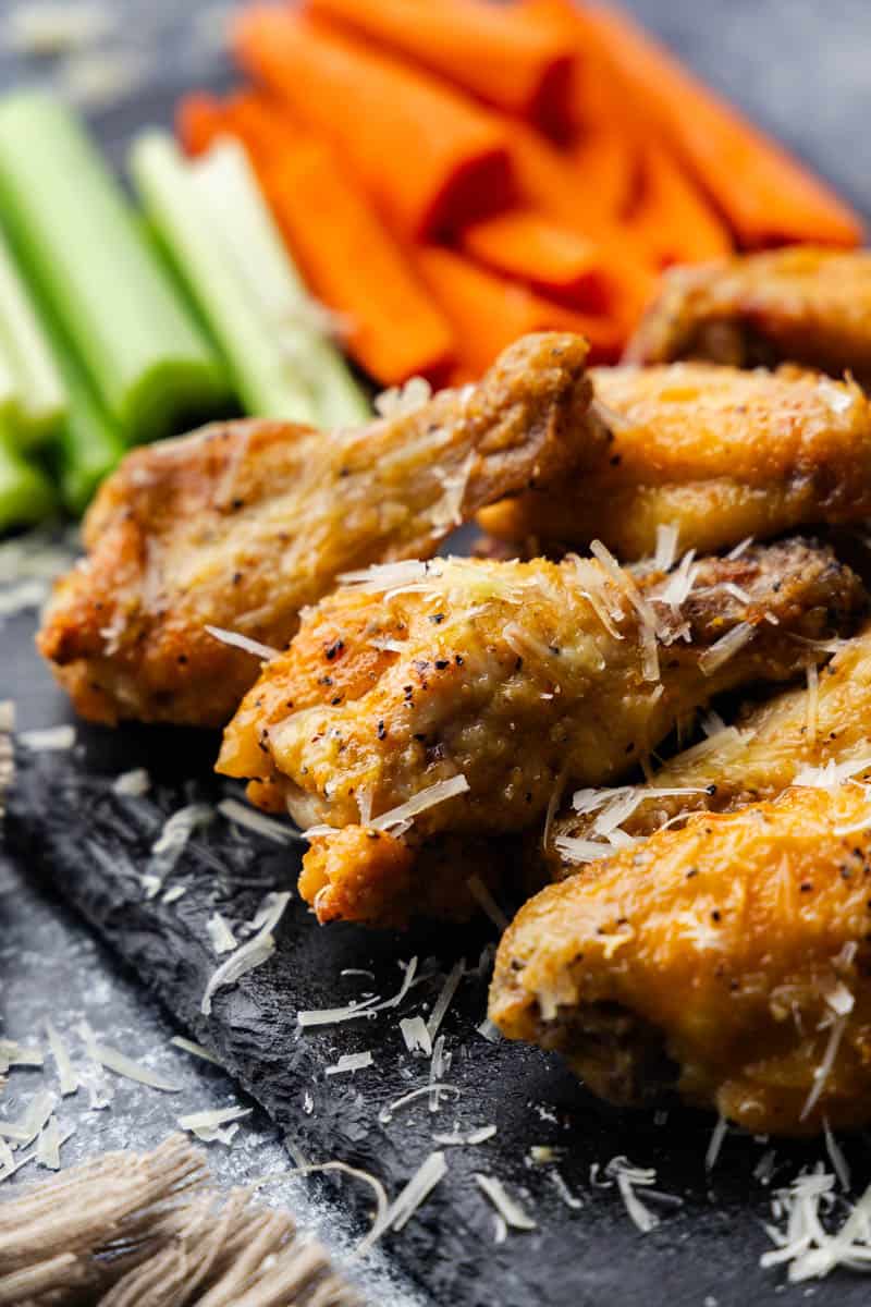 Garlic parmesan chicken wings on a black platter.