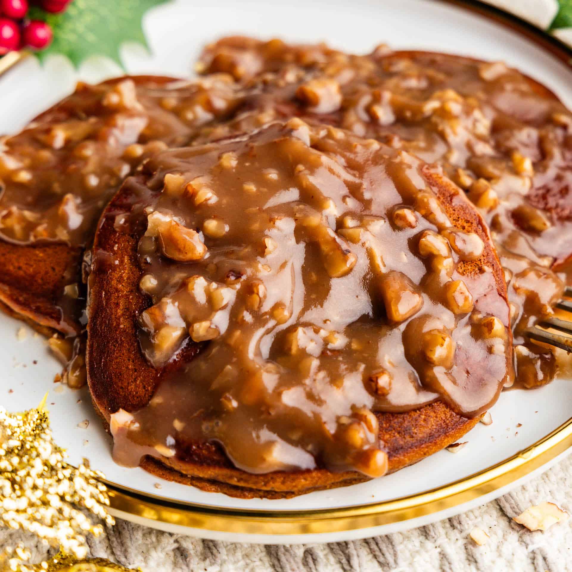 Gingerbread pancakes on a plate covered with butter pecan syrup.